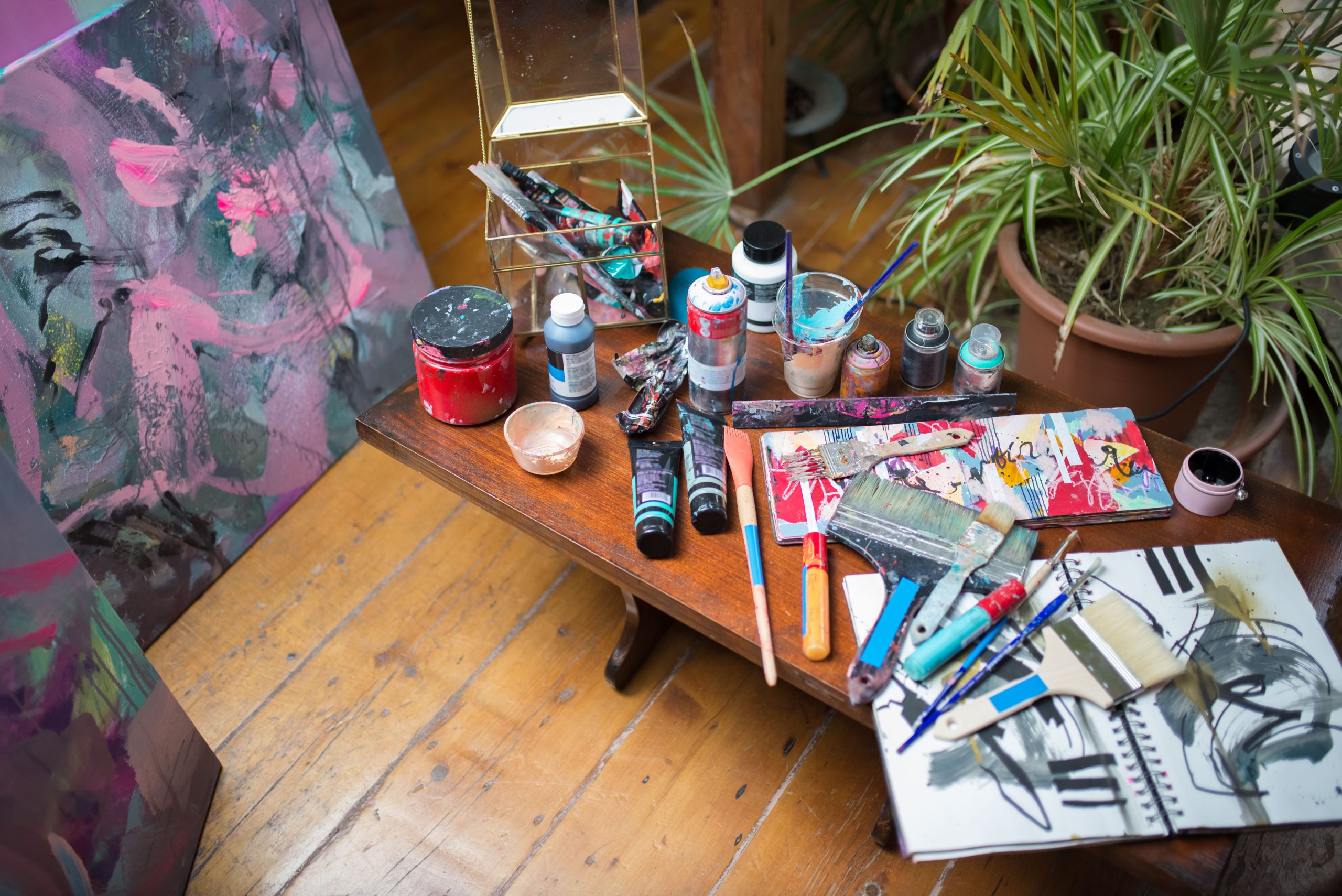 Colorful art supplies and abstract paintings in a cozy artist's studio